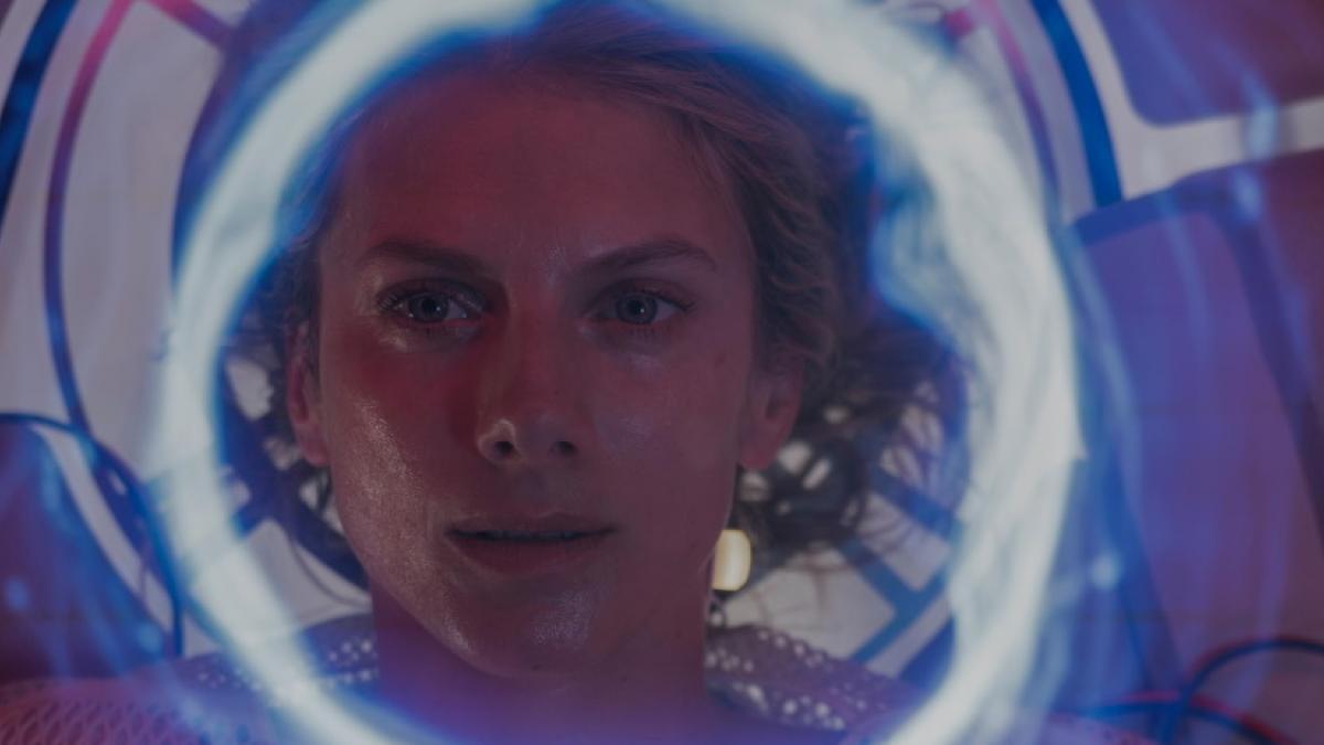 A close-up of a woman's face surrounded by a halo of blue light.